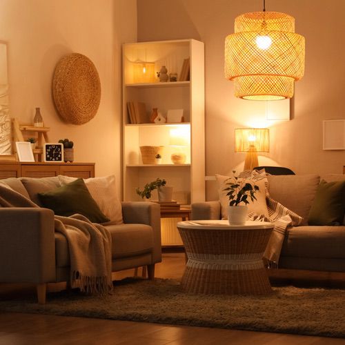 Living room featuring two grey sofas, a round wicker coffee table, and a tiered woven pendant light providing cosy mood lighting.