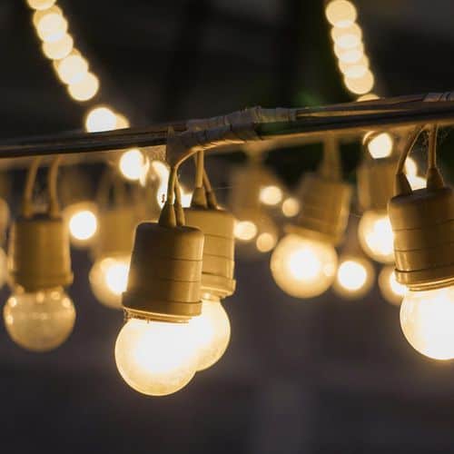 A string of glowing Edison-style bulbs hanging against a dark background, perfect for hygge outdoor lighting ideas.
